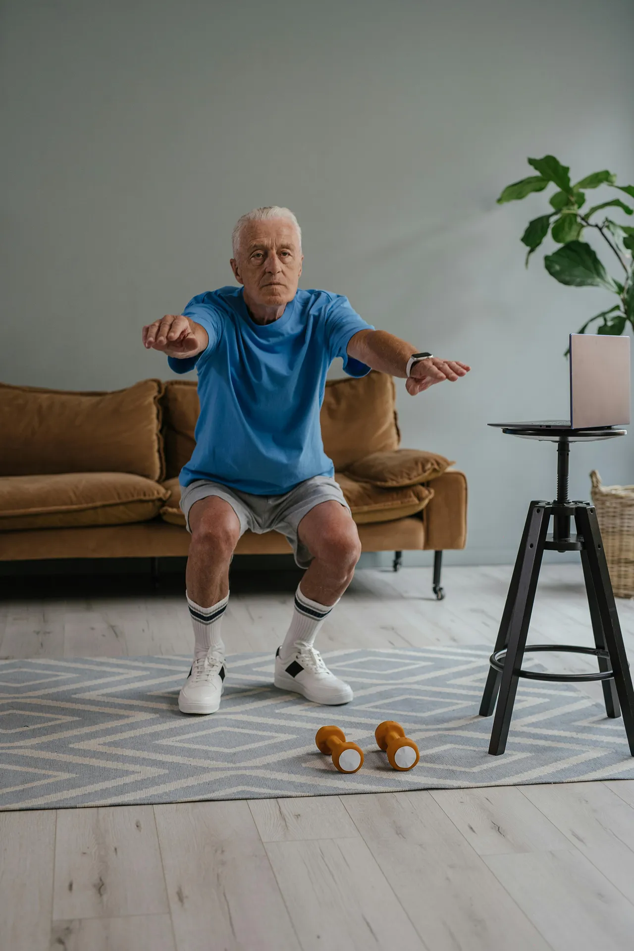 Man die een online valpreventie cursus volgt in de woonkamer